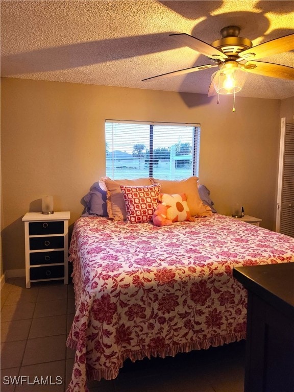 tiled bedroom featuring ceiling fan and a textured ceiling