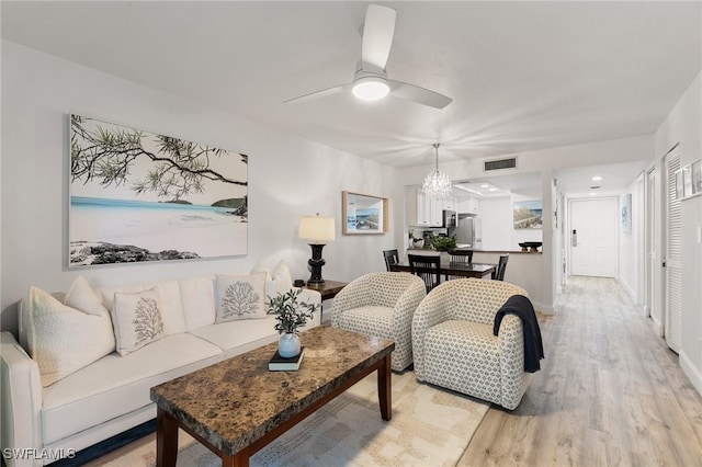 living room with ceiling fan with notable chandelier and light wood-type flooring