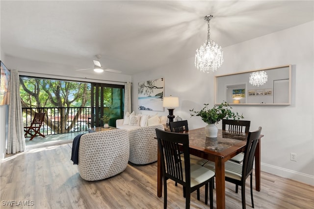 dining space featuring wood-type flooring and ceiling fan with notable chandelier