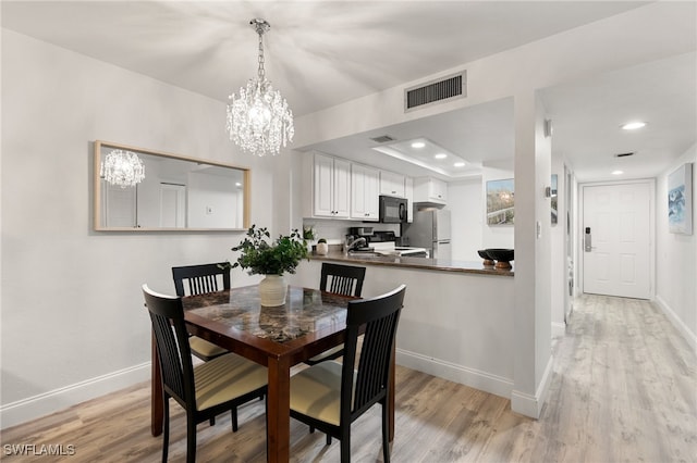 dining area with light hardwood / wood-style floors and a notable chandelier