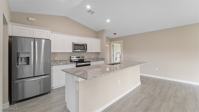 kitchen with appliances with stainless steel finishes, white cabinetry, a kitchen island with sink, and lofted ceiling