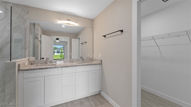 bathroom featuring tiled shower, vanity, hardwood / wood-style flooring, and ceiling fan