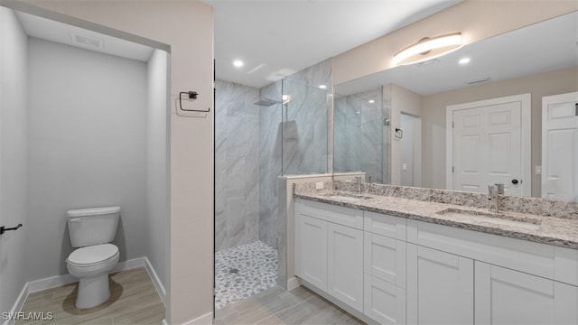 bathroom with hardwood / wood-style flooring, vanity, toilet, and tiled shower