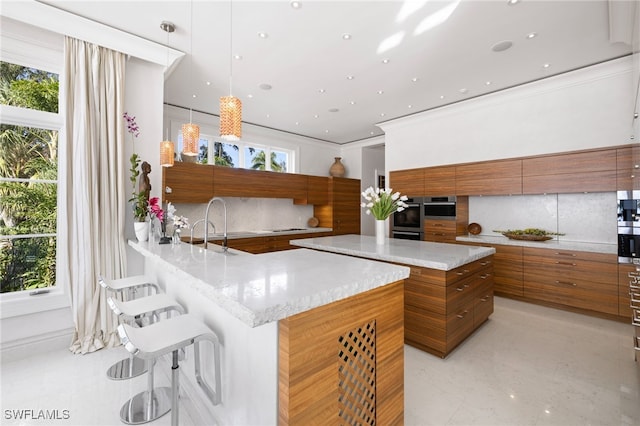 kitchen featuring a wealth of natural light, decorative light fixtures, a breakfast bar, and backsplash