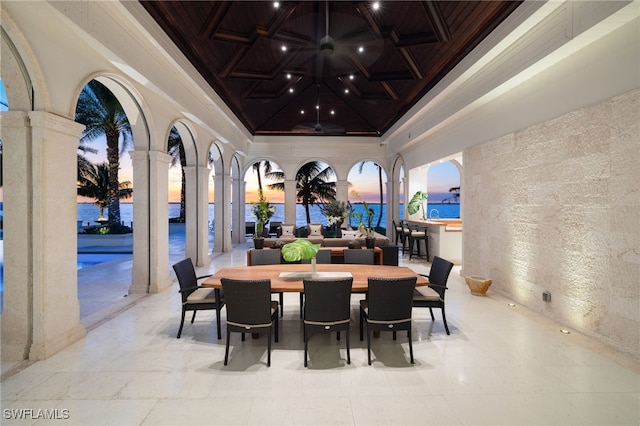 dining space with coffered ceiling, a water view, ornamental molding, beamed ceiling, and decorative columns