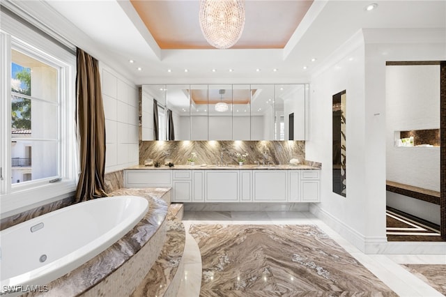 bathroom featuring a bathing tub, vanity, decorative backsplash, a raised ceiling, and a chandelier