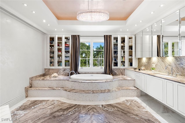 bathroom with vanity, a bathtub, a tray ceiling, and backsplash