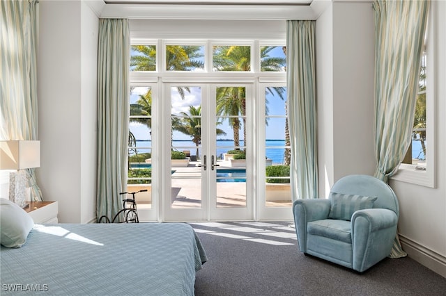 bedroom featuring a water view, carpet flooring, multiple windows, and access to outside