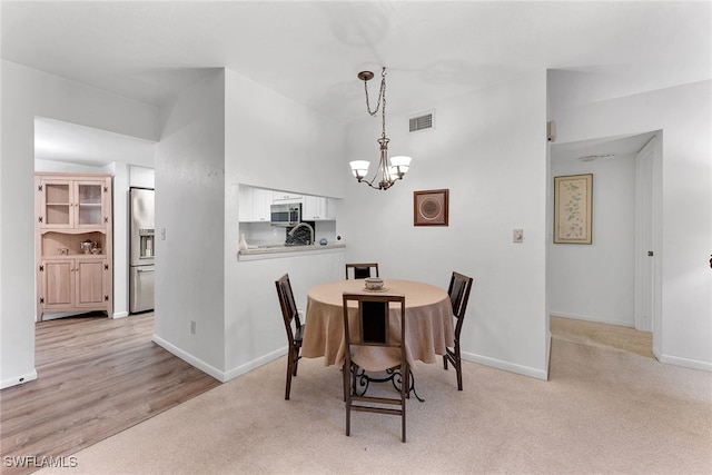 dining area featuring a notable chandelier and light wood-type flooring