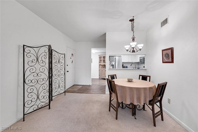 dining space featuring light carpet, a chandelier, and sink