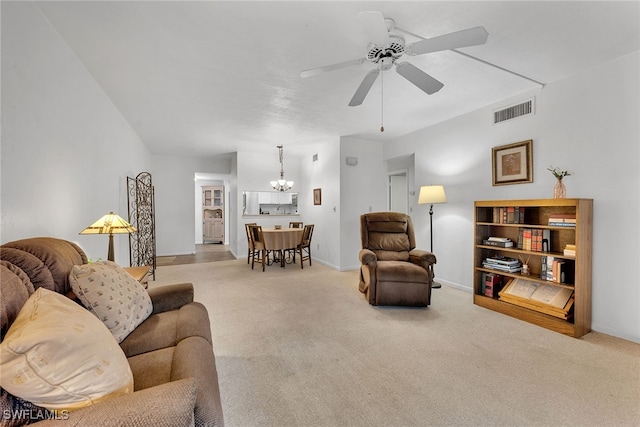 carpeted living room with ceiling fan with notable chandelier