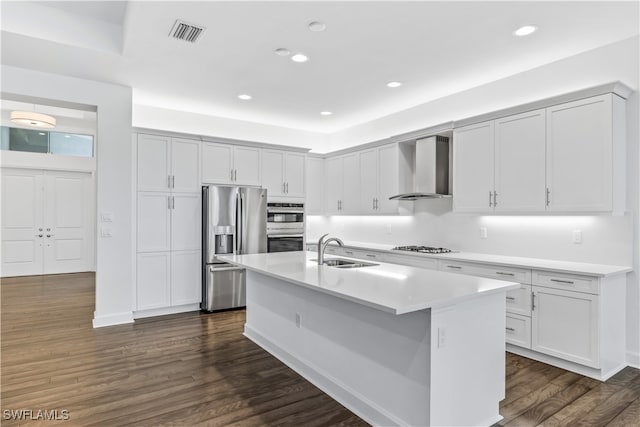 kitchen with a center island with sink, wall chimney range hood, sink, dark hardwood / wood-style flooring, and stainless steel appliances