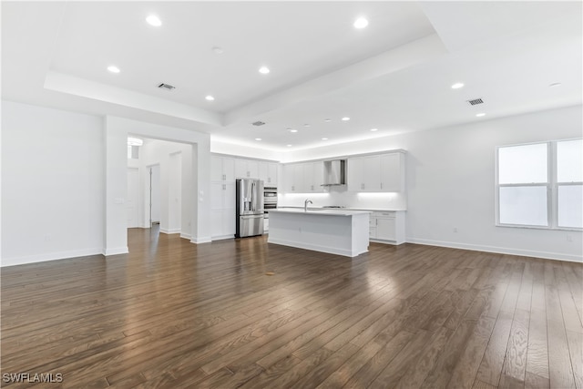 unfurnished living room with a raised ceiling, sink, and dark hardwood / wood-style floors