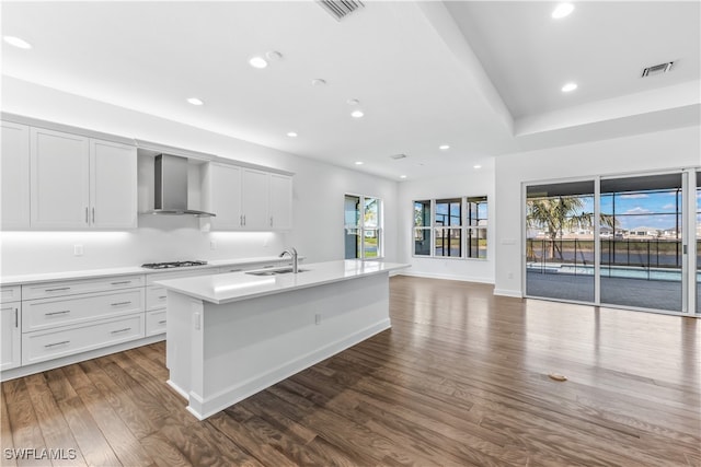 kitchen with a healthy amount of sunlight, dark hardwood / wood-style flooring, wall chimney range hood, and stainless steel gas cooktop