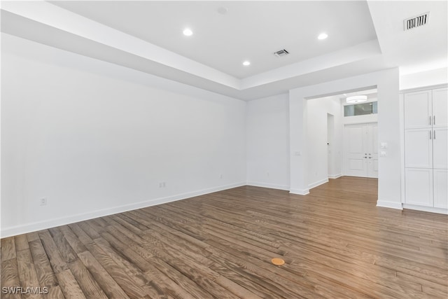 unfurnished room with a raised ceiling and light wood-type flooring