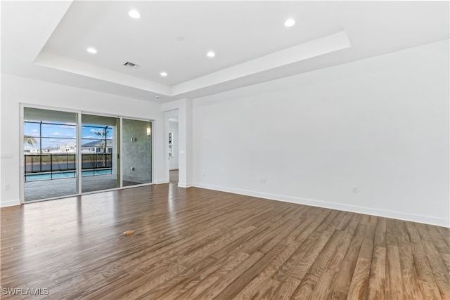 spare room with hardwood / wood-style floors and a tray ceiling