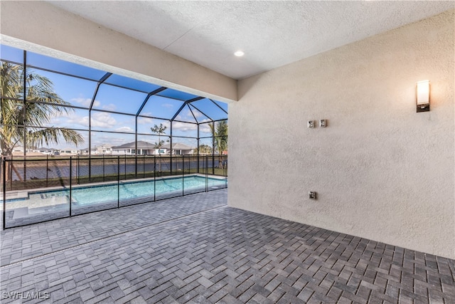 view of swimming pool featuring glass enclosure and a patio area