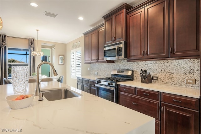 kitchen featuring decorative backsplash, appliances with stainless steel finishes, ornamental molding, sink, and decorative light fixtures