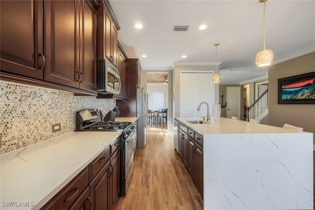 kitchen with sink, hanging light fixtures, light hardwood / wood-style flooring, appliances with stainless steel finishes, and ornamental molding