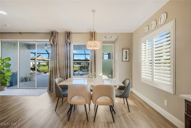 dining space featuring an inviting chandelier, ornamental molding, and light hardwood / wood-style flooring