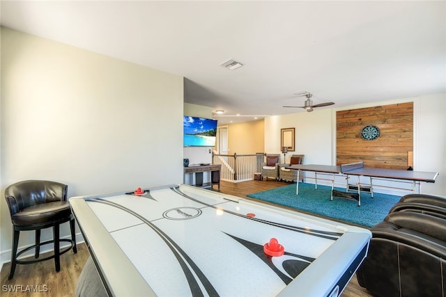 recreation room with ceiling fan, wood walls, and hardwood / wood-style flooring