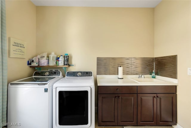 clothes washing area with washing machine and dryer, sink, and cabinets