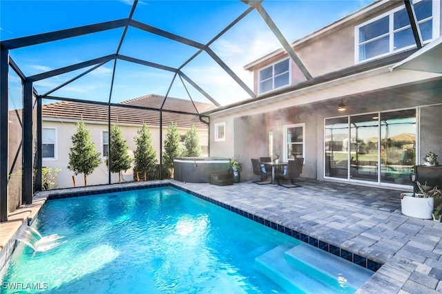 view of swimming pool with pool water feature, glass enclosure, a patio, and a hot tub