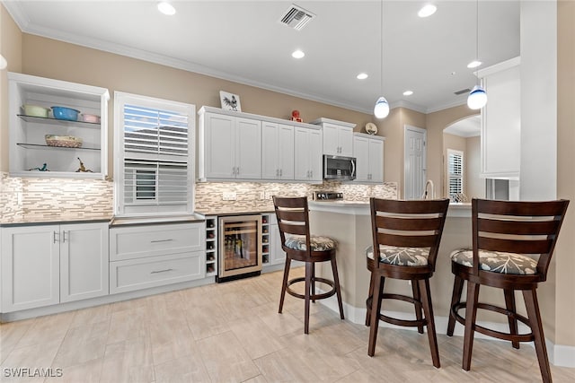 kitchen featuring white cabinets, a kitchen breakfast bar, hanging light fixtures, and beverage cooler