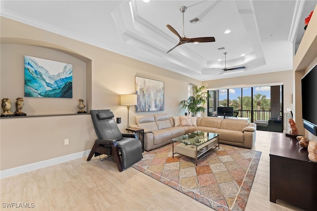 living room featuring a raised ceiling, ceiling fan, and crown molding