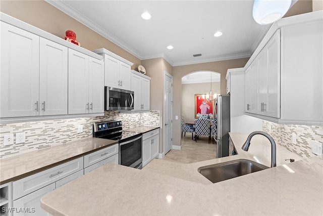 kitchen with sink, hanging light fixtures, stainless steel appliances, crown molding, and white cabinets