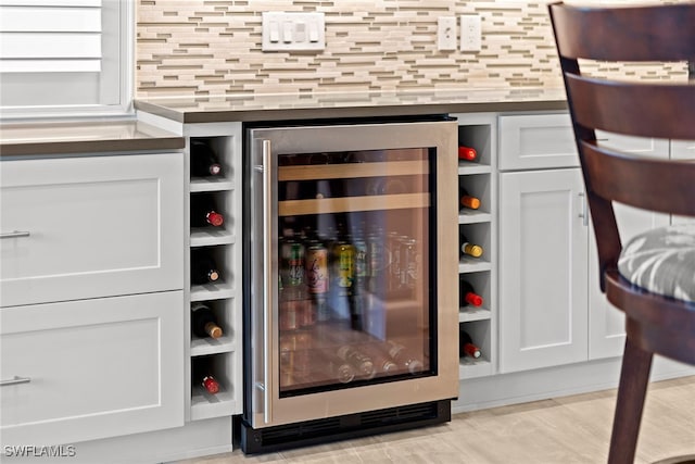 interior details with white cabinetry, beverage cooler, and tasteful backsplash