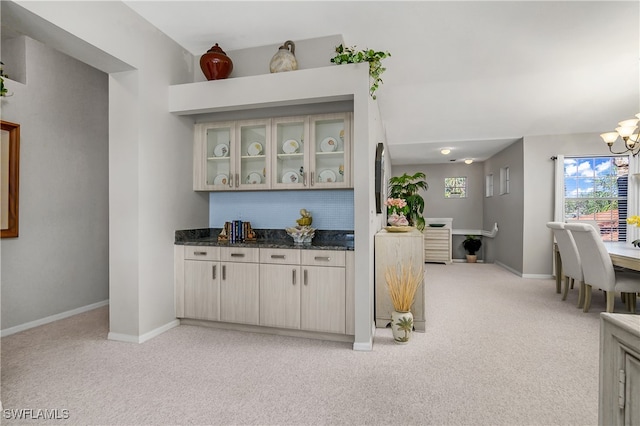 bar featuring light carpet, cream cabinets, dark stone counters, and an inviting chandelier