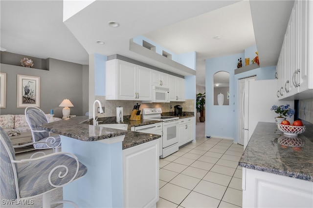 kitchen with kitchen peninsula, decorative backsplash, white appliances, sink, and white cabinetry