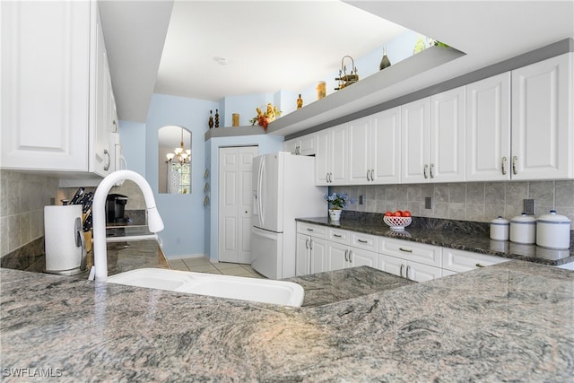 kitchen with white cabinets, backsplash, white fridge with ice dispenser, and sink