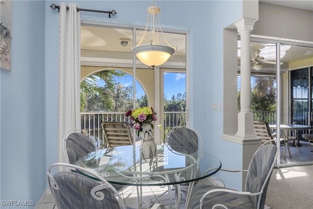 carpeted dining space featuring ceiling fan and ornate columns