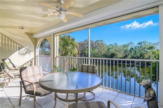 sunroom with a water view and ceiling fan