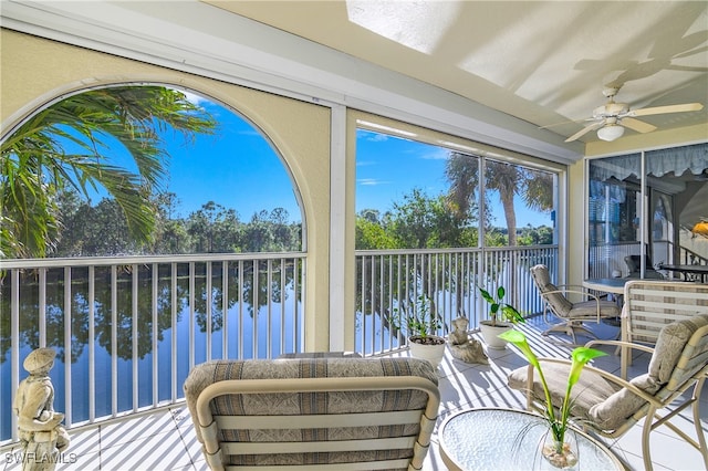 sunroom featuring ceiling fan and a water view