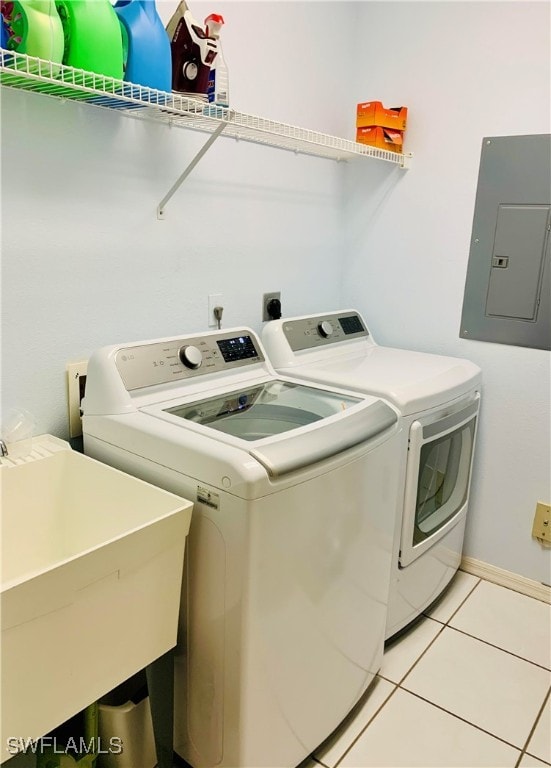 laundry room featuring light tile patterned floors, washing machine and dryer, electric panel, and sink