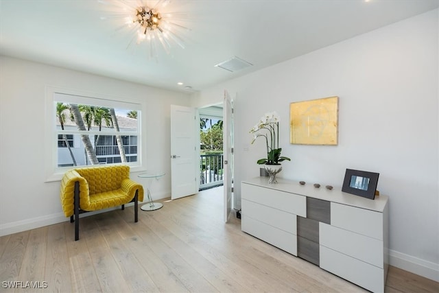 living area featuring light wood-type flooring and an inviting chandelier