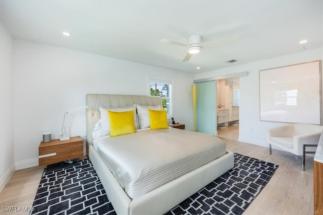 bedroom with connected bathroom, light hardwood / wood-style flooring, and ceiling fan