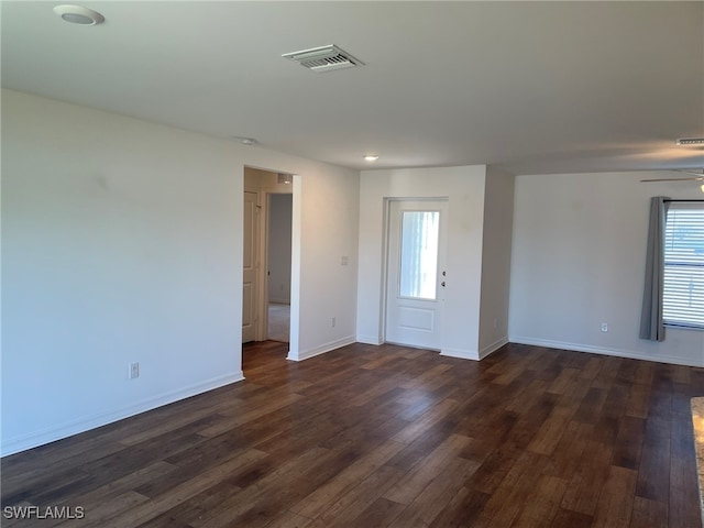 empty room featuring ceiling fan, dark wood-type flooring, and a healthy amount of sunlight