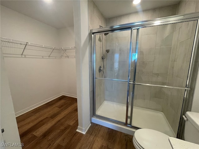 bathroom featuring toilet, wood-type flooring, and walk in shower