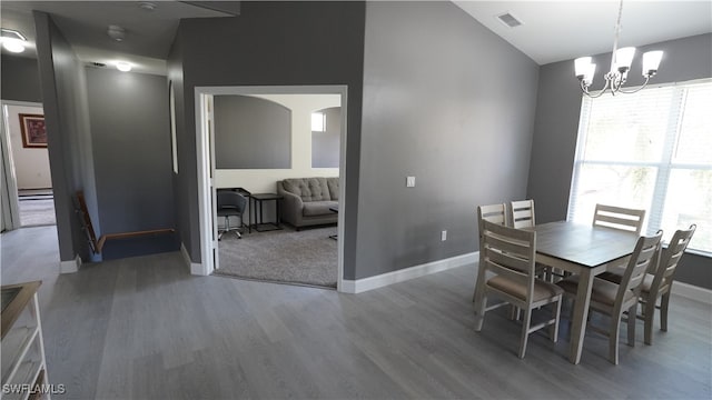 dining space with hardwood / wood-style floors, a baseboard heating unit, and a notable chandelier