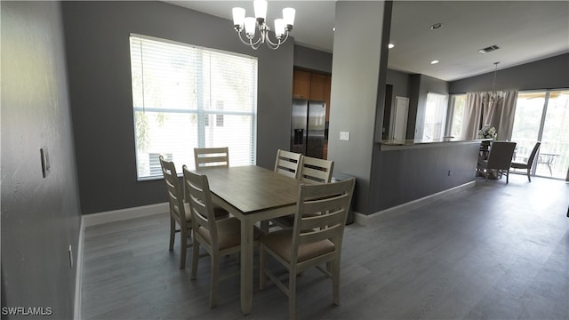 dining space featuring hardwood / wood-style flooring, a healthy amount of sunlight, and a notable chandelier