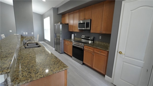 kitchen featuring stone counters, sink, stainless steel appliances, kitchen peninsula, and light wood-type flooring