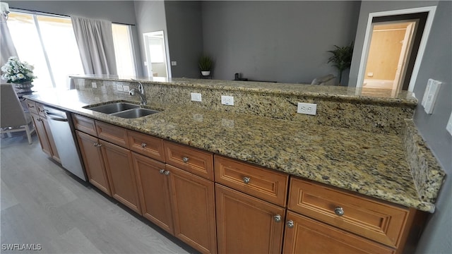 kitchen featuring stainless steel dishwasher, light stone counters, and sink