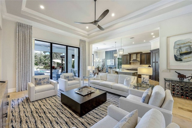 living room featuring a tray ceiling, crown molding, ceiling fan with notable chandelier, and light wood-type flooring