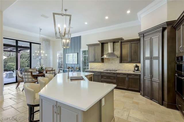 kitchen featuring a large island with sink, a wealth of natural light, sink, and wall chimney exhaust hood