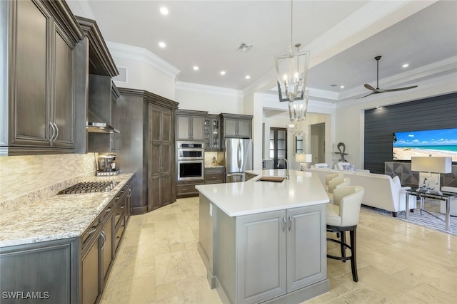 kitchen with a large island, stainless steel appliances, pendant lighting, decorative backsplash, and ceiling fan with notable chandelier