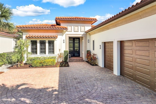 view of exterior entry featuring a garage and french doors